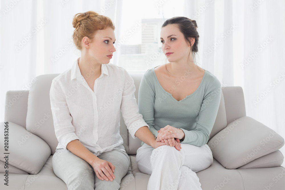 Woman consoling female friend while sitting on sofa Woman consoling female friend while sitting on sofa