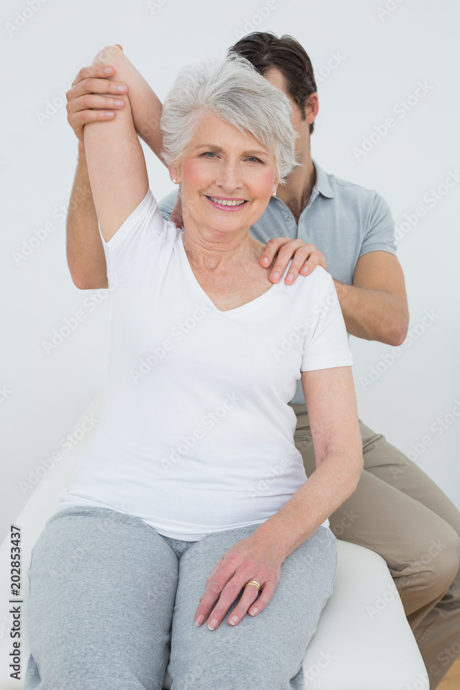 Physiotherapist stretching a smiling senior womans arm Physiotherapist stretching a smiling senior womans arm