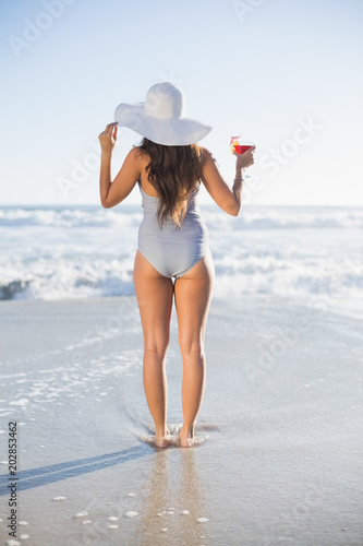 Rear view of woman in swimsuit with straw hat holding cocktail © WavebreakmediaMicro