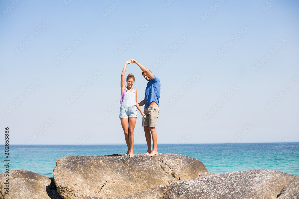 Young couple dancing on rock by sea