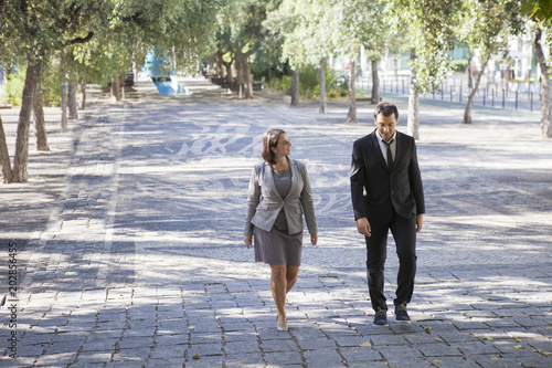 Fotografie Optimistic business colleagues walking over street and chatting
