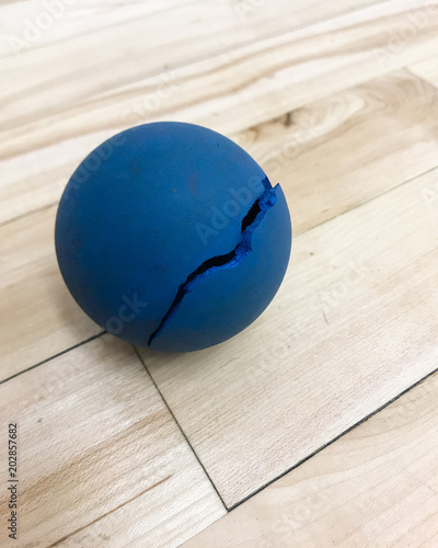 Broken blue racquetball on court floor