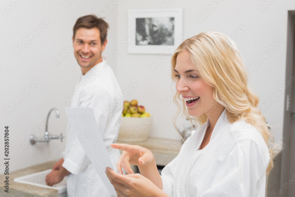 Surprised woman looking at document with man in kitchen Surprised woman looking at document with man in kitchen