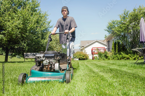 Teenage boy mowing lawn photo