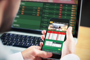 Businessman using smartphone against gambling app screen