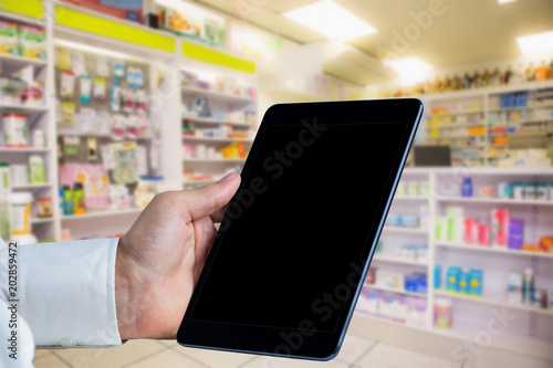 Man using tablet pc against close up of shelves of drugs