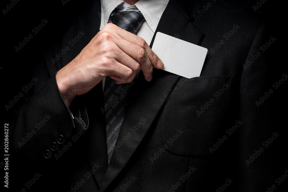 Εκτύπωση καμβά Close up of man in black suit holding business card on black background