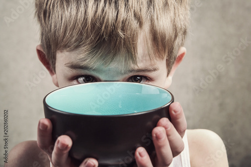 Photo Child holding an empty bowl, hunger concept