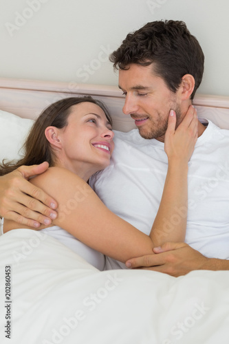 Loving young couple lying in bed