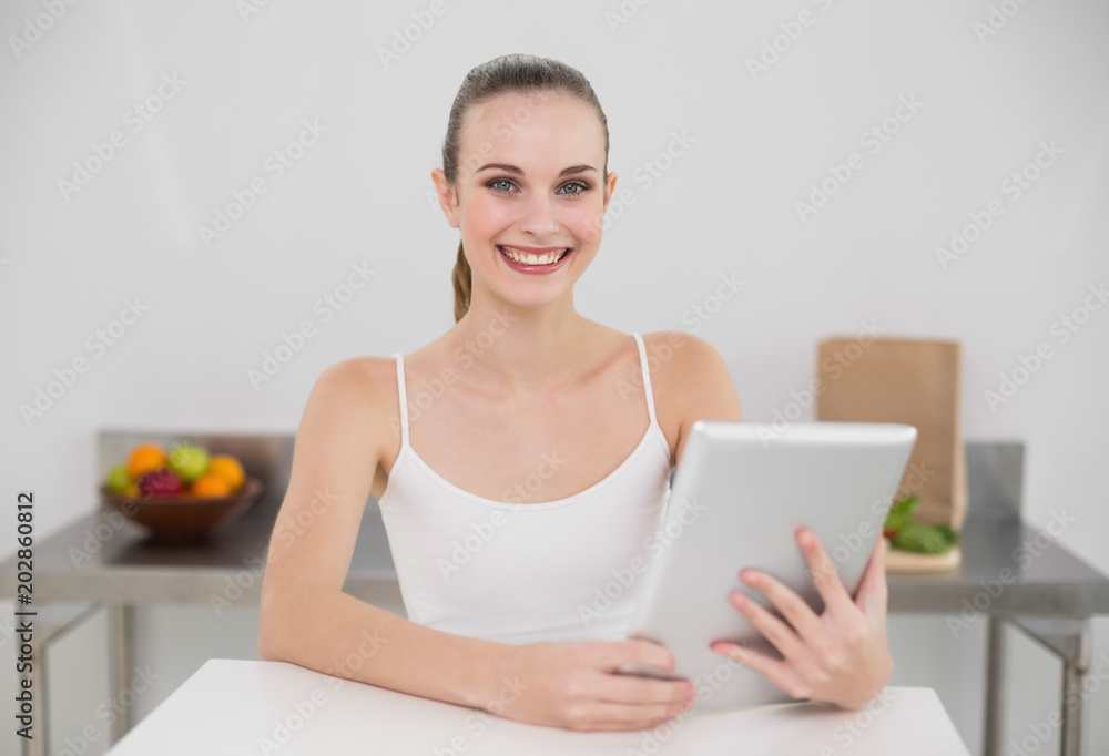Smiling young woman using her tablet pc looking at camera Smiling young woman using her tablet pc looking at camera