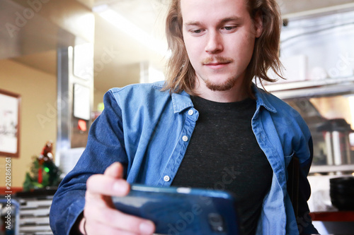 Young man at a restaurant looking at his phone photo