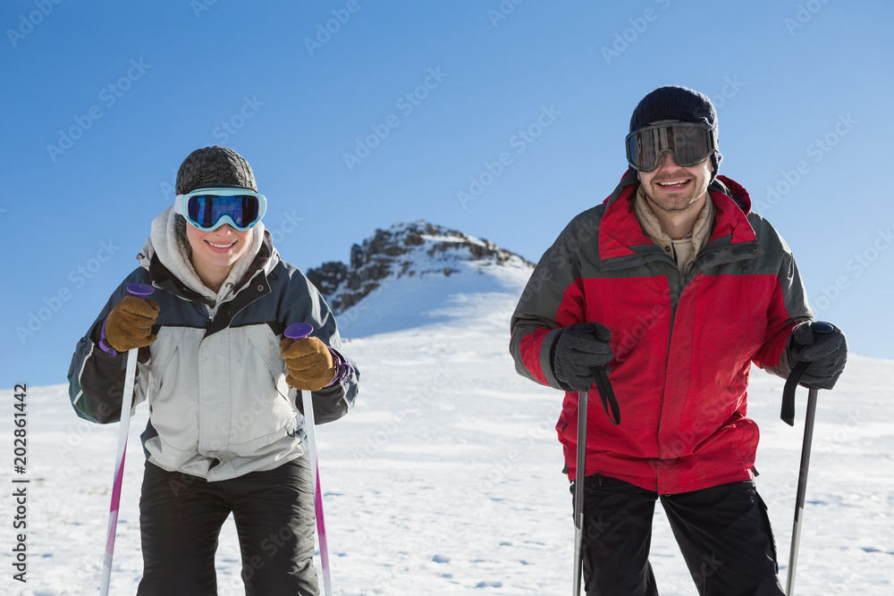 Portrait of a smiling couple with ski poles on snow