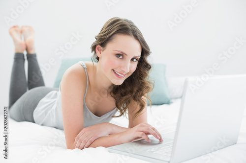 Casual brunette using laptop in bed