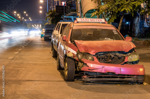 Crashed car stands on a road in the city center. Damaged taxi in the night city.