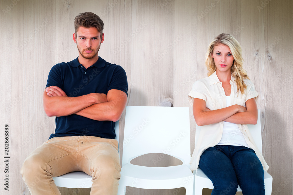 Young couple sitting in chairs not talking during argument against wooden planks Young couple sitting in chairs not talking during argument against wooden planks