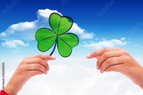 Shamrock against bright blue sky with clouds