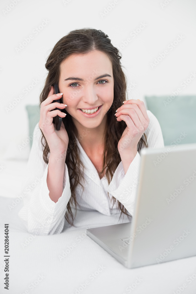 Casual woman using cellphone and laptop in bed Casual woman using cellphone and laptop in bed