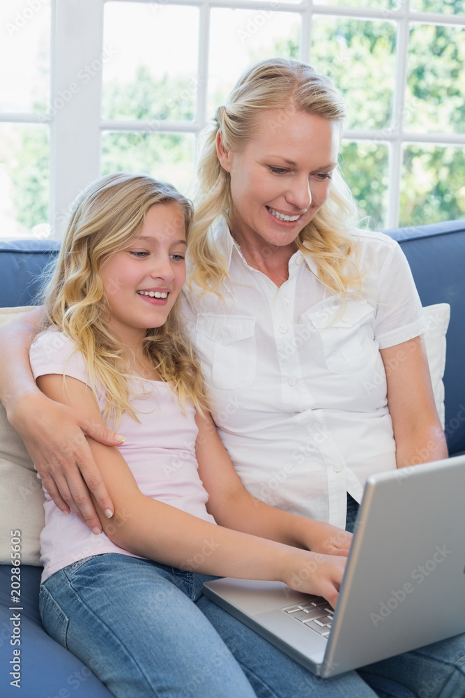 Mother and daughter using laptop on sofa Mother and daughter using laptop on sofa