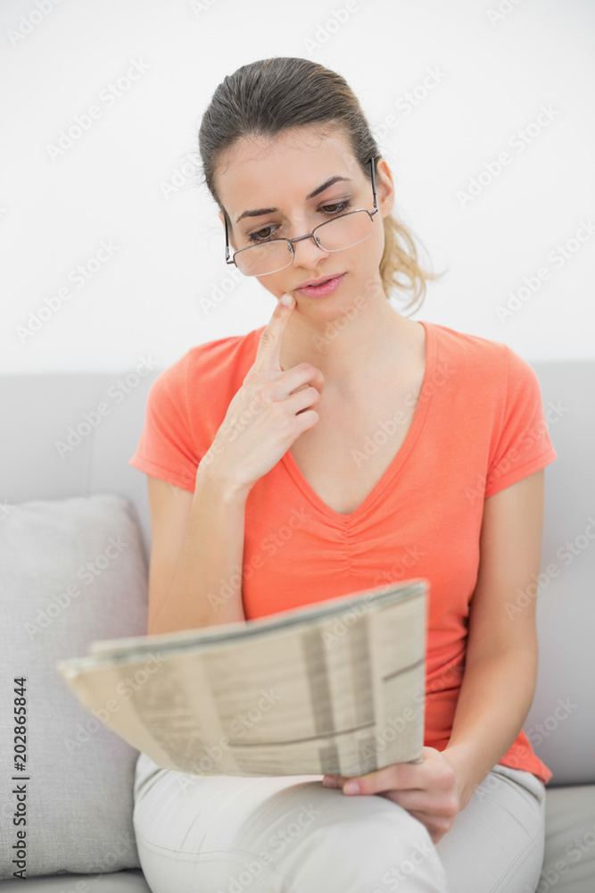 Attractive woman reading a magazine sitting on couch Attractive woman reading a magazine sitting on couch