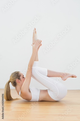 Attractive toned woman lying on floor stretching her leg