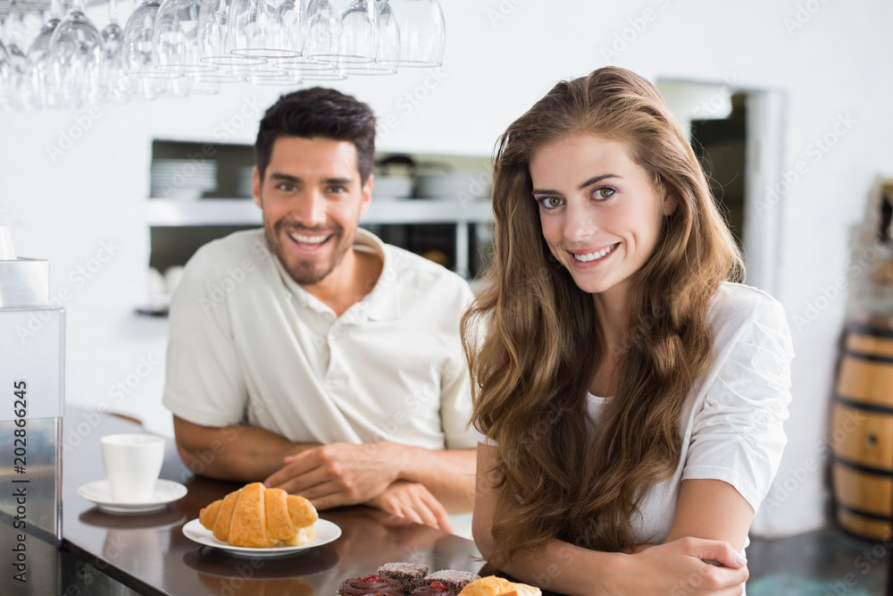 Smiling couple with coffee and croissant at coffee shop