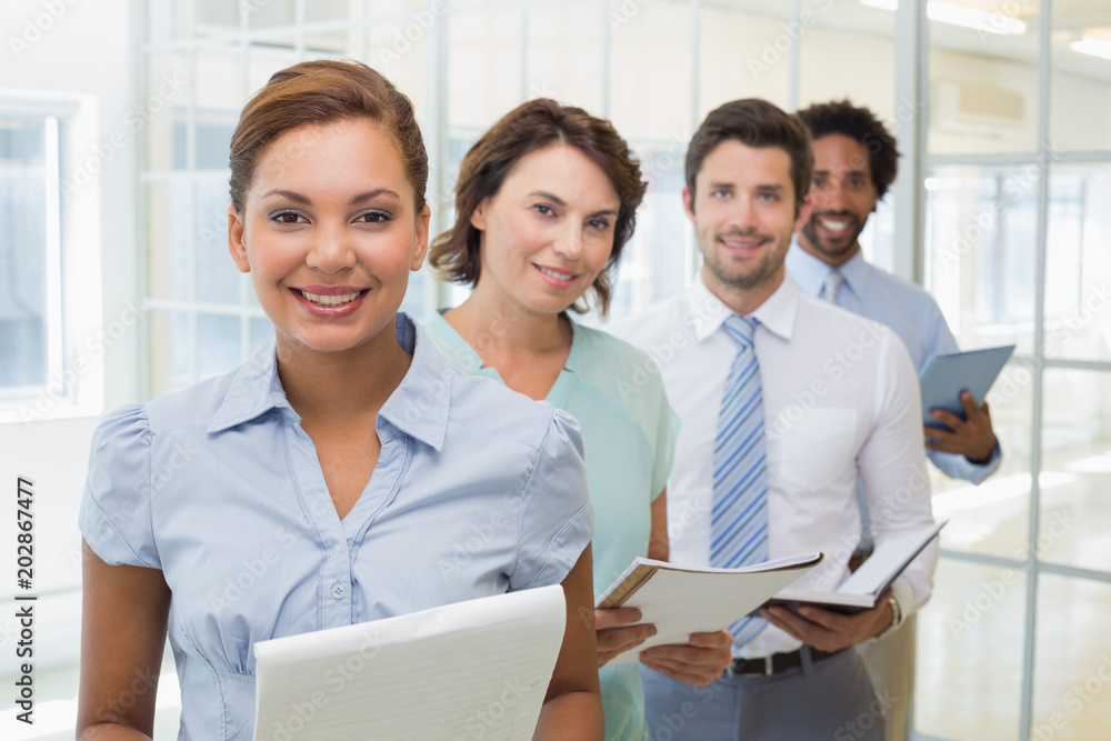 Business colleagues holding notepads in row at office Business colleagues holding notepads in row at office