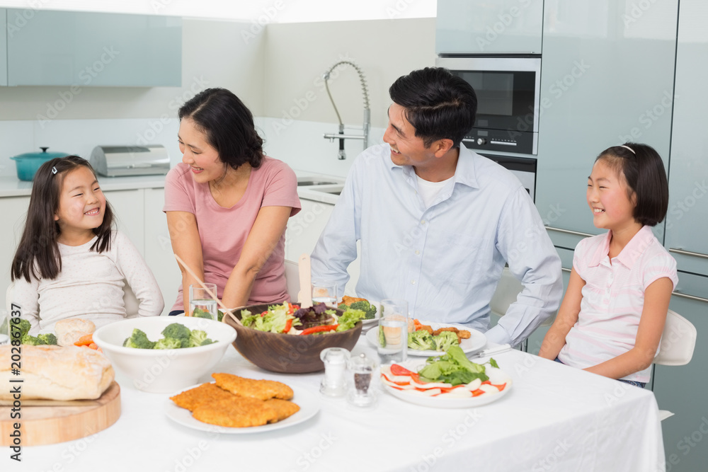 Family of four enjoying healthy meal in kitchen