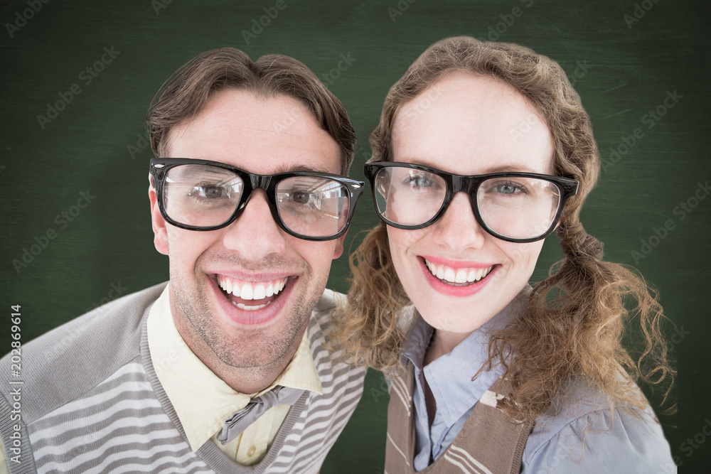 Happy geeky hipster smiling at camera against green chalkboard Happy geeky hipster smiling at camera against green chalkboard