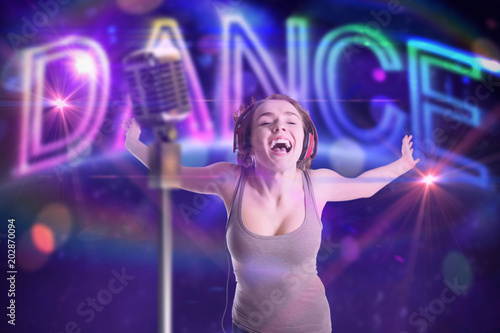 Pretty girl listening to music against digitally generated colourful dance text