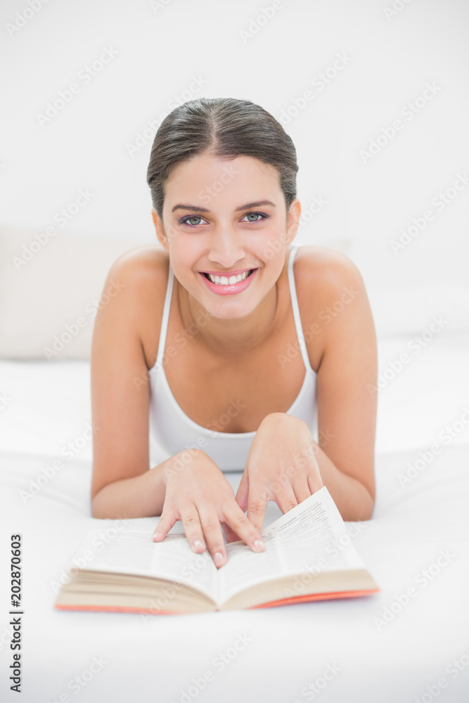 Casual young brown haired model in white pajamas reading a book Casual young brown haired model in white pajamas reading a book