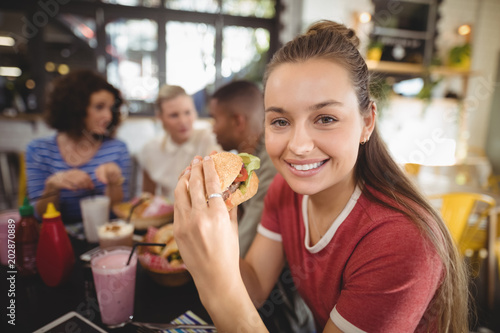 Portrait of smiling beautiful young woman eating burger