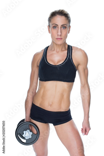 Female bodybuilder holding large black dumbbell with arm down looking at camera