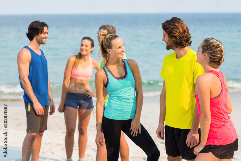 Friends in sports clothing talking while standing at beach Friends in sports clothing talking while standing at beach