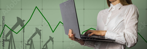 Girl with a laptop in hand and graph chart with the indicator on the oil price slide in the background. The concept of rising oil prices and stock trading.