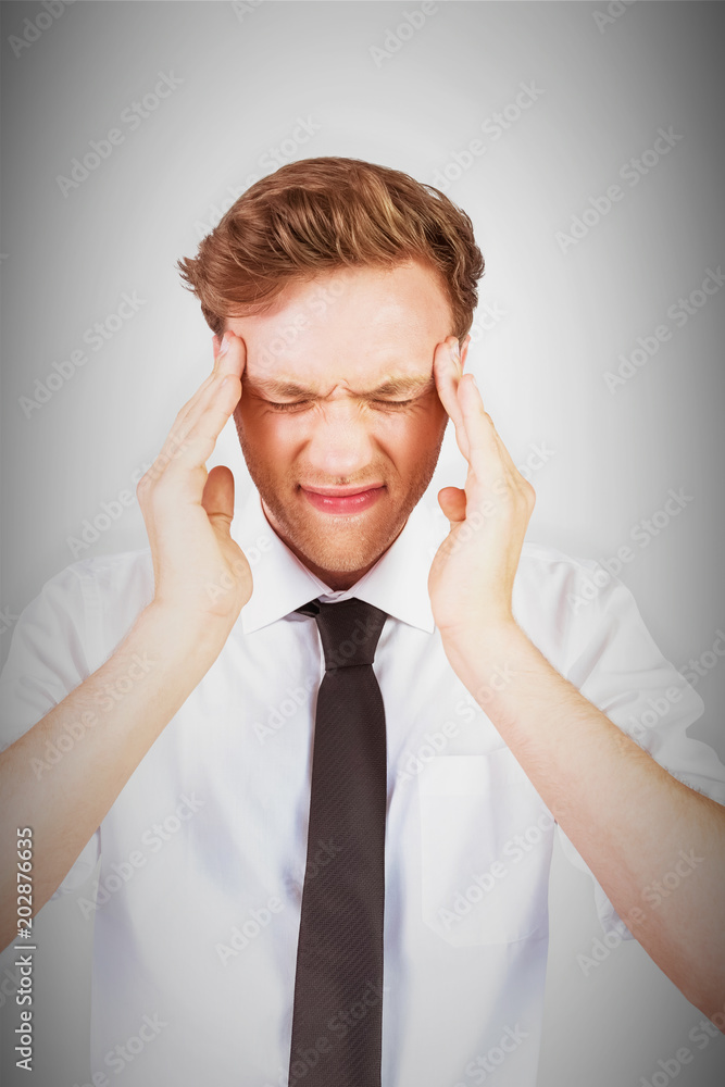 Young businessman getting a headache against grey vignette Young businessman getting a headache against grey vignette