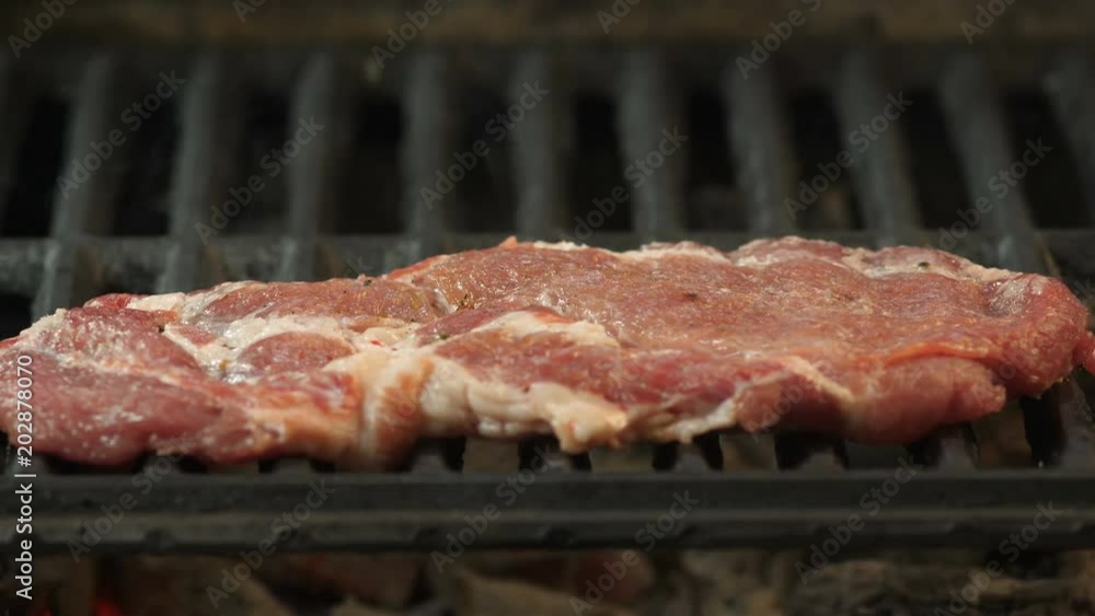 The chef puts fried steak, steak marinated with spices and sprinkled with olive oil with a sprig of thyme and rosemary, grilled in the kitchen of the restaurant, video on the close-up side, smoke from The chef puts fried steak, steak marinated with spices and sprinkled with olive oil with a sprig of thyme and rosemary, grilled in the kitchen of the restaurant, video on the close-up side, smoke from