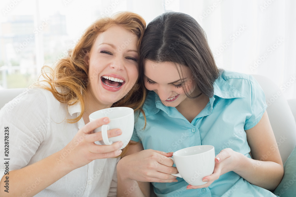 Friends with coffee cups enjoying a conversation at home Friends with coffee cups enjoying a conversation at home