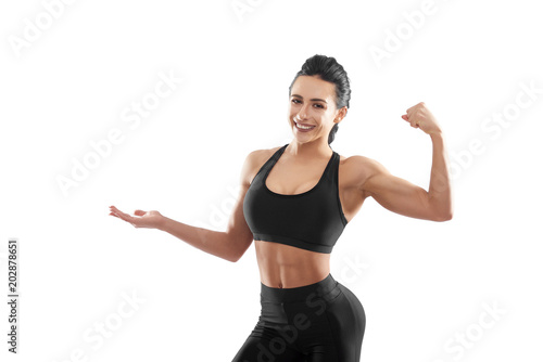 Strong athletic model posing on white background. Girl having strong, fit, curvy body, healthy and stunning figure. looking like fitness coach. Looking positive, smiling, feeling happy and satisfied. photo
