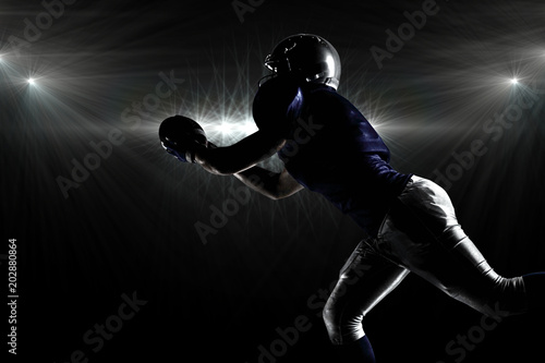 Silhouette American football player catching ball against spotlight © vectorfusionart