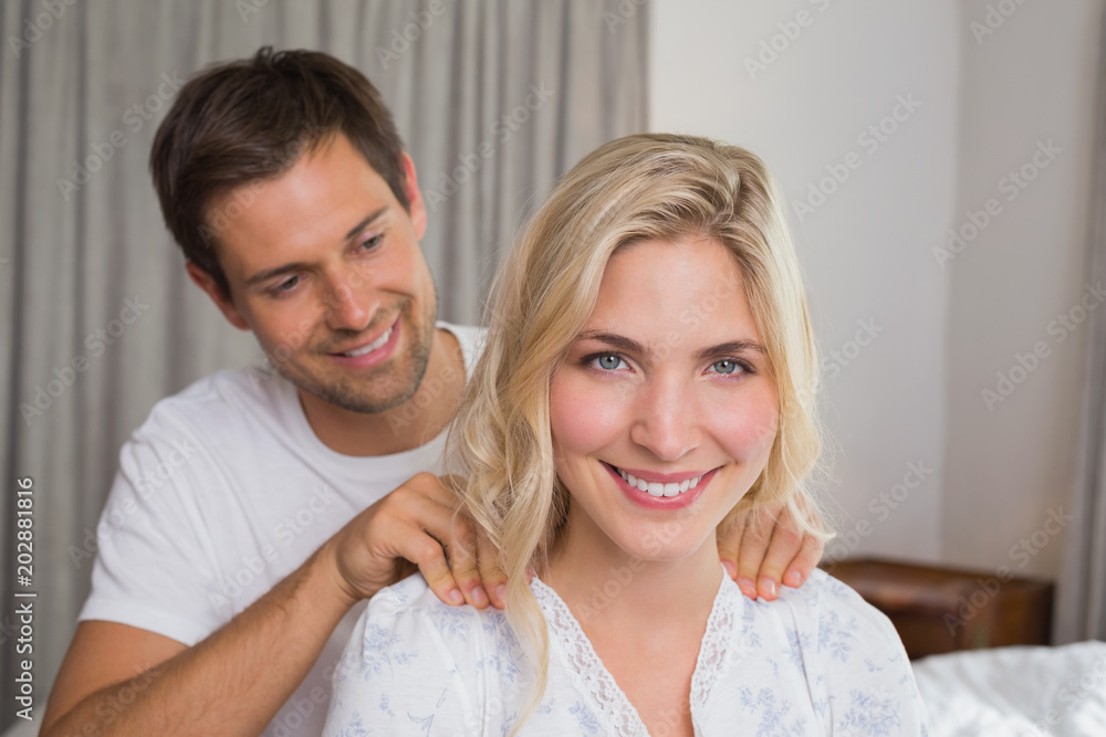 Smiling young man massaging womans shoulders