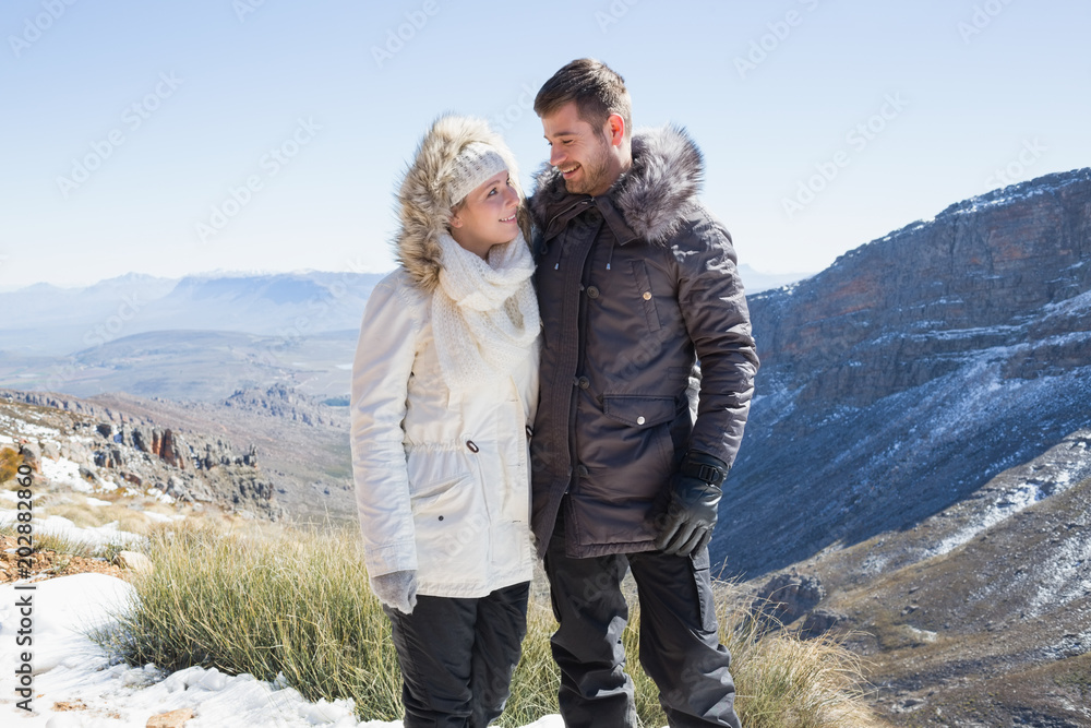 Couple in fur hood jackets against mountain range
