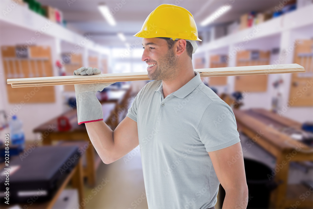 Worker with plank of wood against workshop Worker with plank of wood against workshop