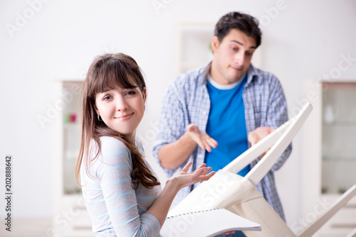 Wife helping husband to repair broken chair at home