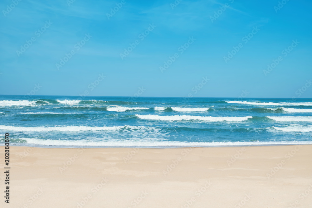 Sandy beach and choppy waves. White sand, blue sky and crystal sea of tropical beach