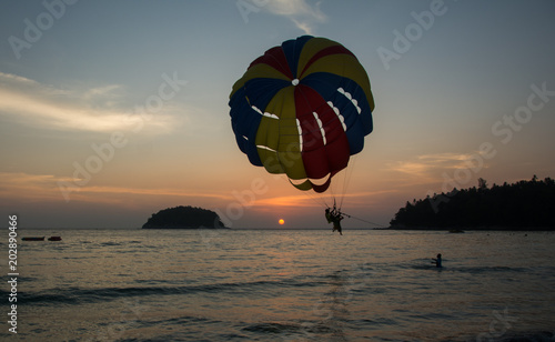 Two men landing on paraseiling on sunset, extreme sports