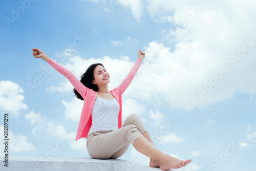 Freedom concept. Enjoyment. Asian young woman relaxing under blue sky on rooftop