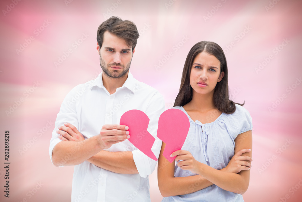 Upset couple holding two halves of broken heart against digitally generated pink girly design