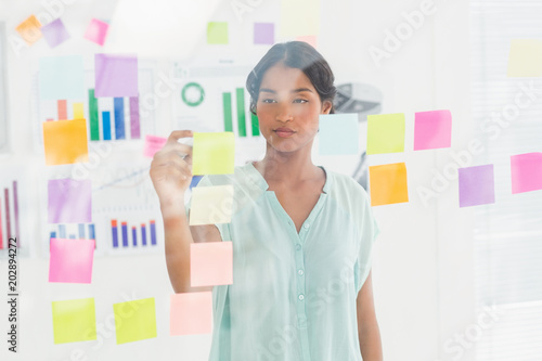  Concentrated businesswoman looking post its on the wall