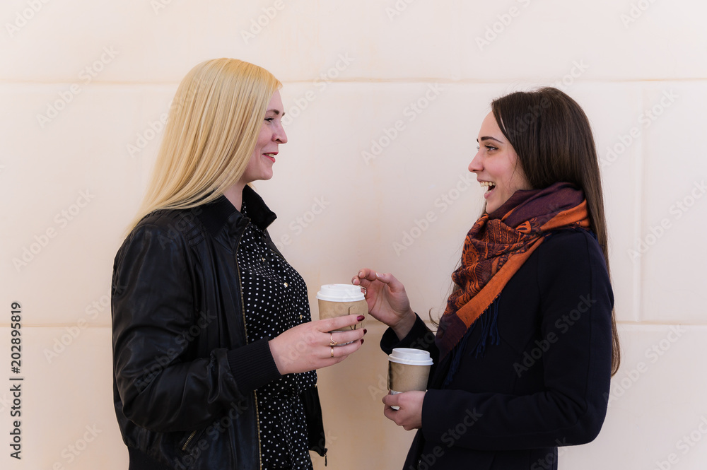 Two girlfriends holding paper cups and gossiping Two girlfriends holding paper cups and gossiping