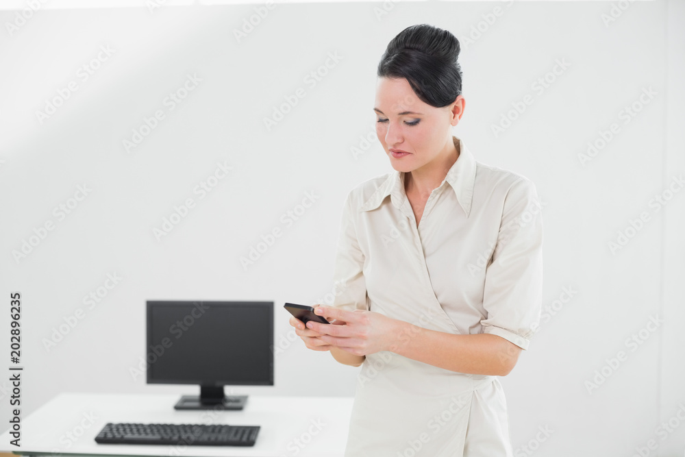 Businesswoman looking at cellphone in office Businesswoman looking at cellphone in office